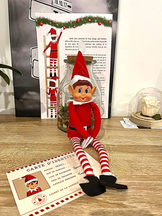 Lutin farceur assis sur une table en bois devant sa lettre d'arrivée affichée et sa carte d'identité posée au sol