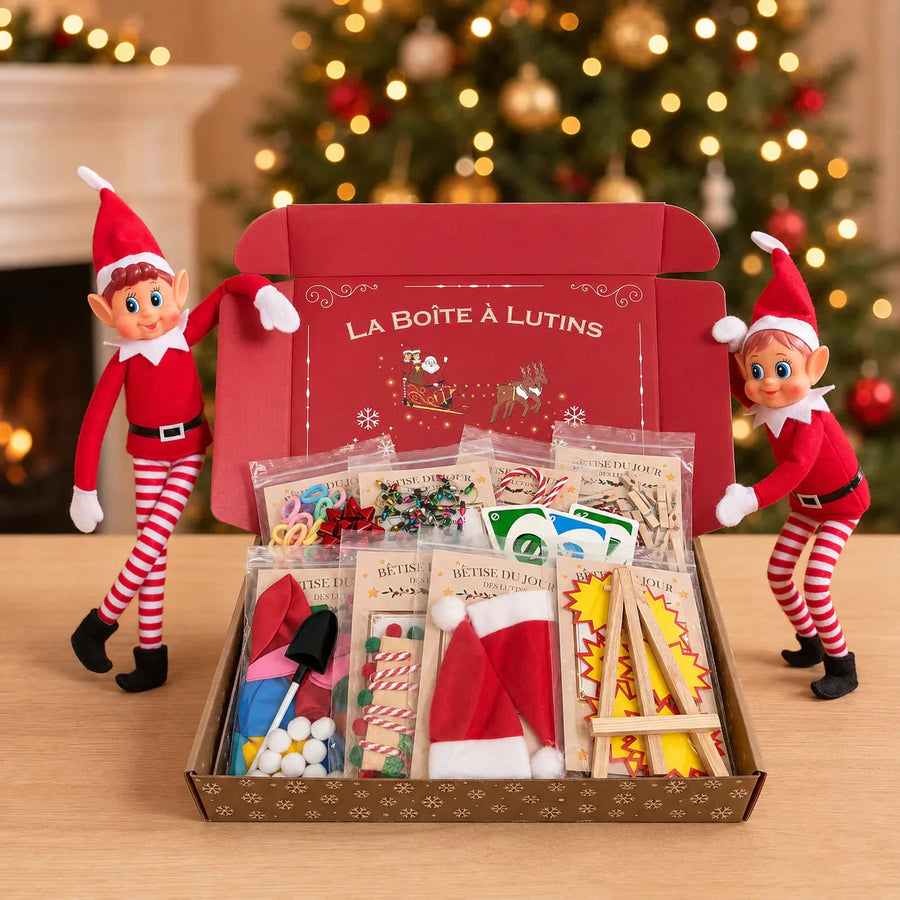 Box complète 24 bêtises Lutin Farceur 2026 ouverte, entourée de deux lutins farceurs devant un sapin de Noël
